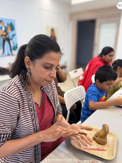 A participant carefully sculpts the fine details of her clay idol, completely absorbed in the mindful and tactile process of creation.