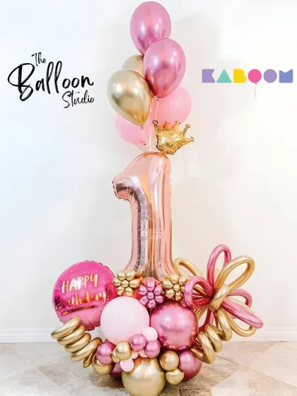 A princess-perfect first birthday bouquet in shades of pink and gold, complete with a crown on top of the number one balloon.