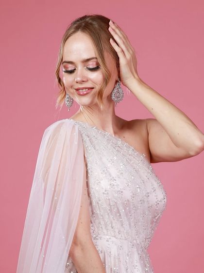 A delicate portrait of Irina Rudakova with her eyes closed, showcasing the detailed makeup and the texture of her elegant white gown.