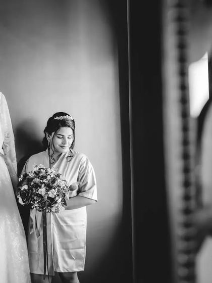 A wider black and white shot of the bride with her dress, framed by a decorative mirror. This adds an element of artistry to the getting-ready narrative.
