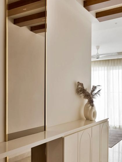 A close-up of the elegant foyer unit and the tall, gold-framed mirror, reflecting the warm wooden rafters on the ceiling.