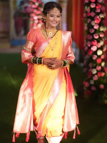 A joyful shot of the bride walking, her yellow and pink Nauvari saree creating a beautiful silhouette.