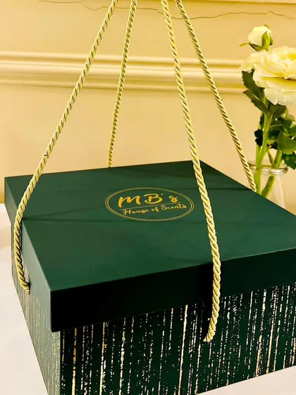 This is my elegant green and gold striped gift box, complete with a rope handle for easy carrying. It's a sturdy and stylish option for presenting a beautiful collection of my scented products.