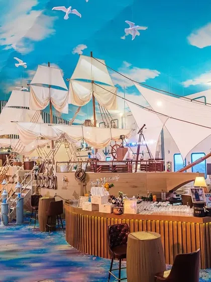 For this nautical-themed birthday, I built a massive ship structure that doubled as the central bar. The design included sails, a ship's wheel, and a sky-painted ceiling with seagulls to make guests feel like they were out at sea.