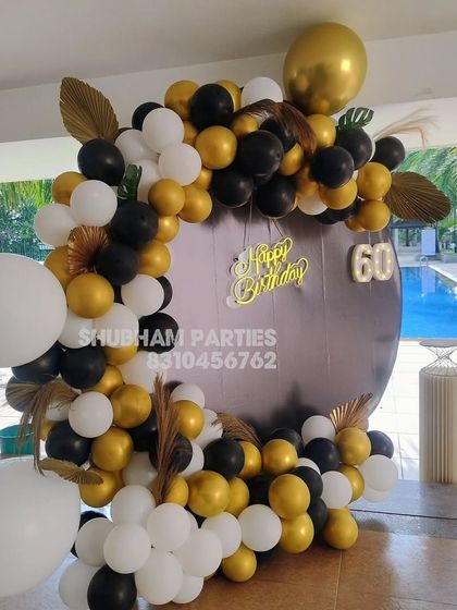 A stylish poolside 60th birthday decoration with a black, white, and gold balloon ring and marquee numbers.