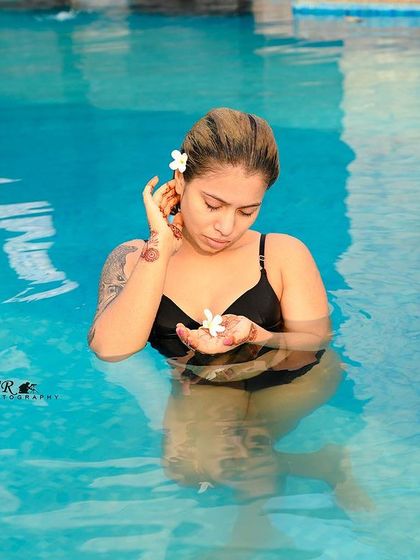 A delicate and thoughtful pose with a flower, adding a touch of nature and softness to the poolside shoot.
