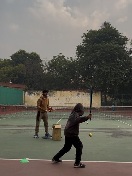 Even our youngest players learn the importance of focus. Here, a young player is practicing his swing with a coach guiding him through every step.