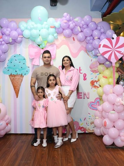 The whole family poses in front of the expansive Candyland backdrop, showcasing the full scale of our thematic decorations.