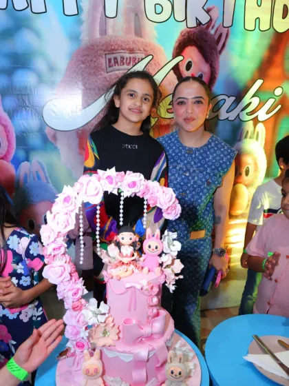 A sweet moment between mother and daughter at the Labubu party. The custom backdrop adds a personal and whimsical touch.