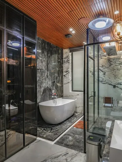This angle shows the full scope of the luxury bathroom, including the smoked glass wardrobe that adds to the room's moody and sophisticated feel.