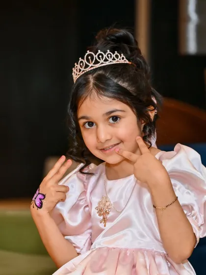 Peace and smiles from the birthday princess. This shot captures her playful personality and the fun details, like the butterfly tattoo on her hand.