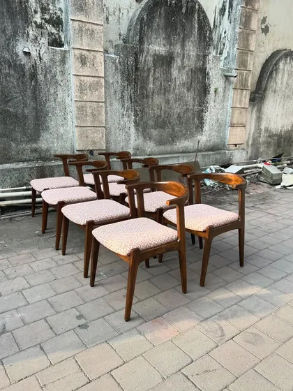 A set of eight mid-century modern dining chairs with curved backrests, ready for a client.