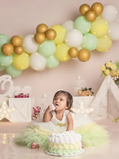 "This is my cake!" A first birthday is a big deal, and this little one is claiming her delicious cake with joy. The soft pastel balloon arch adds a touch of celebration.