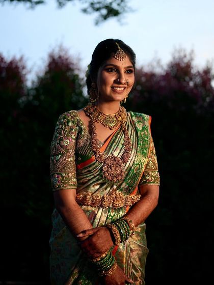 A smiling bride in her green and orange bridal saree. The rich colors and traditional jewelry create a look that is both vibrant and classic.