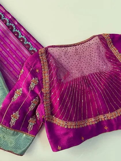 The back of the magenta blouse, showing a sheer panel with sequin work. This adds a modern and glamorous element to the traditional design.