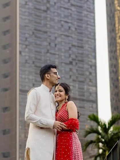 A modern portrait of a couple standing on a bridge, framed by city architecture. The low angle and urban setting give this photo a contemporary and grand feel.