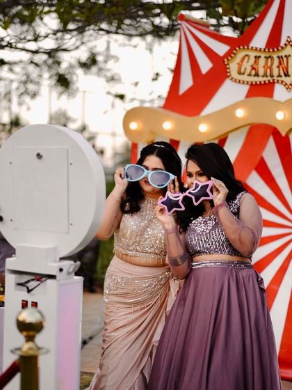 Guests having fun at the photo booth at Neel's carnival party, using oversized novelty glasses as props.