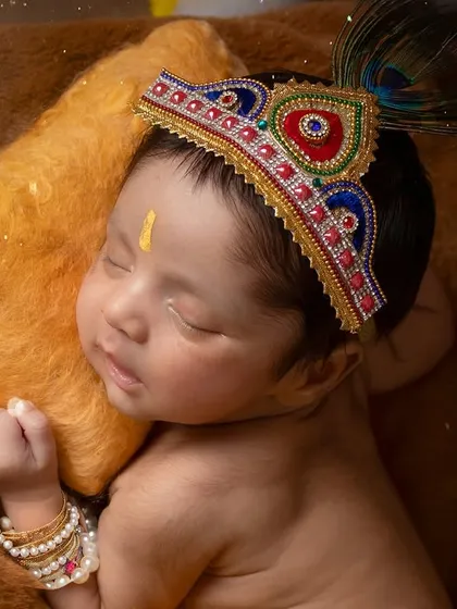 A close-up on the divine details. The intricate crown and the peaceful expression of this newborn Krishna are the focus of this shot.