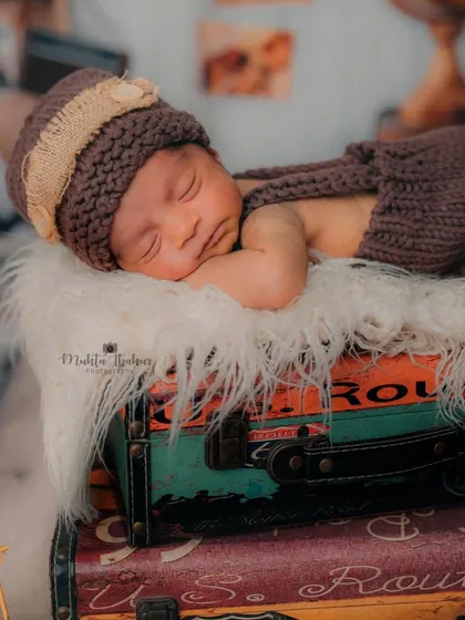 This little one is packed and ready for dreamland. The soft fur and knitted outfit keep him cozy and secure throughout his travel-themed newborn session.