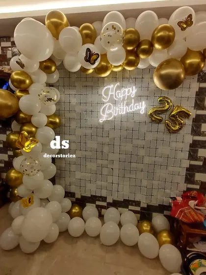 Another perspective of the white and gold 25th birthday setup, showing the full balloon arch.
