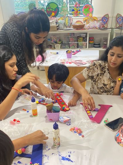 A table full of creativity! This photo captures a group of mothers and children working together on their monogram art projects. It's a beautiful way to bond while making something special.