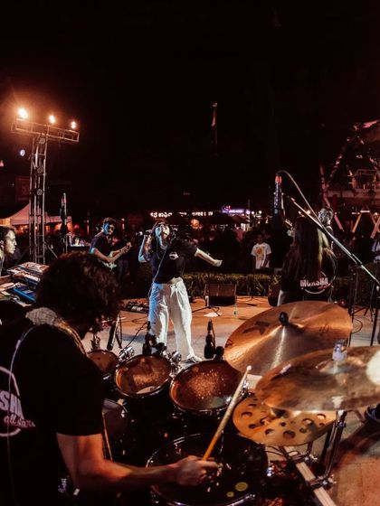 A view from behind the drum kit, looking out at the band and the crowd. This perspective shows the whole team working together to create an amazing live experience.