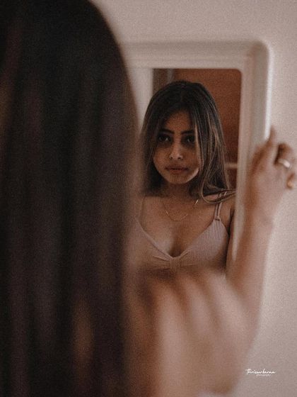 This over-the-shoulder mirror portrait creates a sense of intimacy and introspection. The soft focus and warm tones enhance the mood.