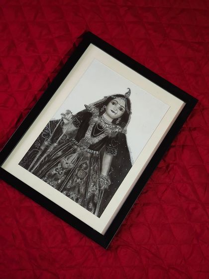 The framed Radha Rani portrait shown at an angle to capture the way light interacts with the graphite. This piece brings a sense of peace and devotion to any room it's in.