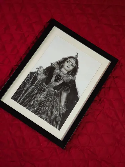 The framed Radha Rani portrait shown at an angle to capture the way light interacts with the graphite. This piece brings a sense of peace and devotion to any room it's in.