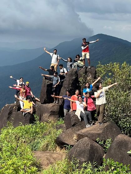 A fun and energetic group photo on the rocky summit of Kurinjal Peak.