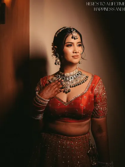 A beautifully lit portrait capturing the bride's elegance. The soft light highlights her features and the rich color of her red lehenga.