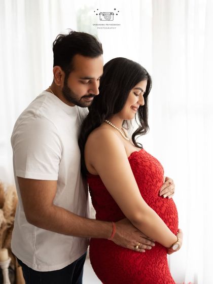 A quiet moment by the window. This back-hug pose is perfect for capturing the protective and loving bond between partners during their pregnancy journey.