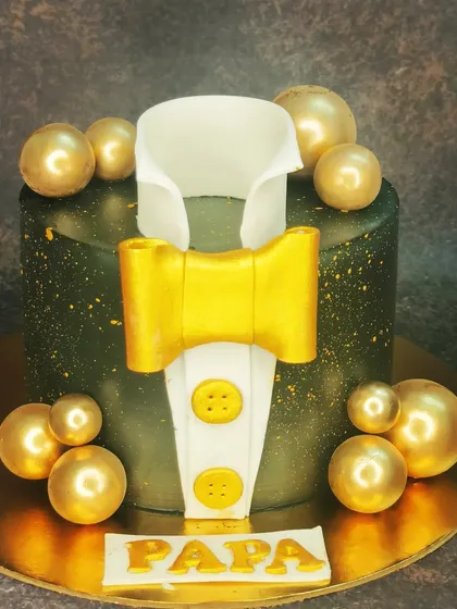 A sophisticated tuxedo cake for a father's birthday. This eggless black forest cake is decorated in black and gold for a sharp and stylish celebration.