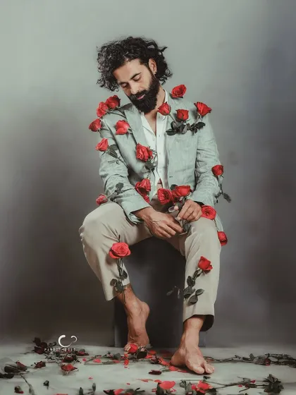 A softer moment within the rose-adorned suit concept. His gentle smile adds a layer of warmth and acceptance to the surreal imagery.