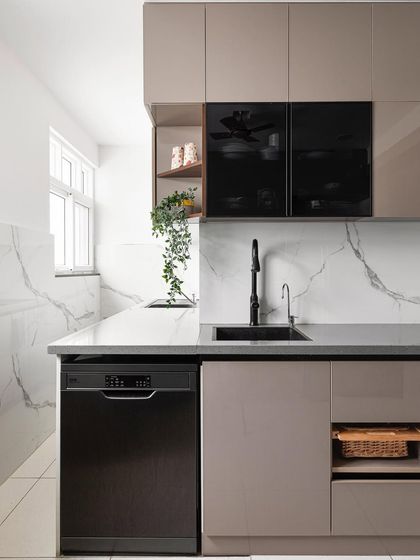 This compact kitchen is packed with modern amenities, including an under-sink RO, dishwasher, and built-in appliances. The design uses glossy acrylic cabinets, glass shutters, and smart accessories like a pantry unit and swing corner to maximize functionality.