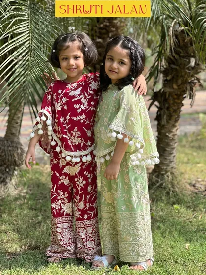There is nothing sweeter than sisterly love, and I adore creating outfits to celebrate it. These two are wearing my coordinated sets, one in a rich maroon and the other in a soft pistachio green, both featuring playful pom-pom details for a touch of fun.