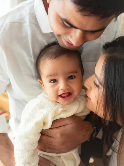 A beautiful close-up of a family sharing a special moment. The focus is entirely on the love and connection between them and their sweet 6-month-old baby.