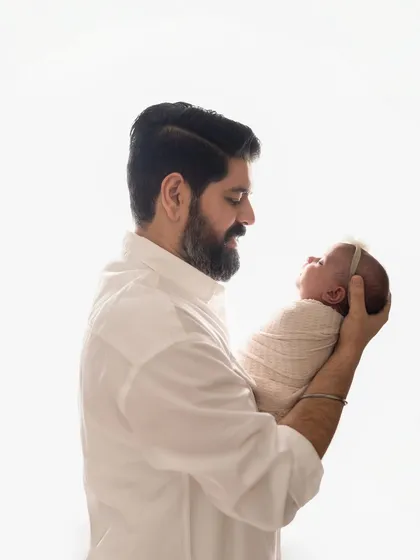 A father holds his newborn baby up, looking at her with so much love. These are the moments that become cherished memories.