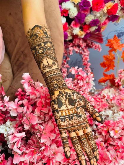 A close-up of one hand, showing the detail in the groom portrait and the surrounding patterns of peacocks and kalash symbols.