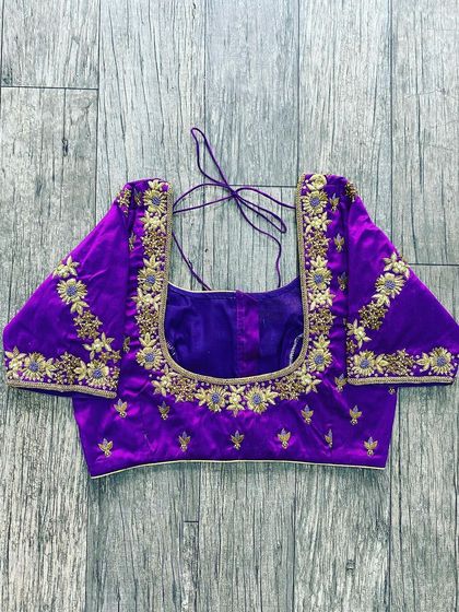 This purple blouse has gold floral embroidery on the neckline and sleeves. The design is classic and can be paired with many types of sarees.