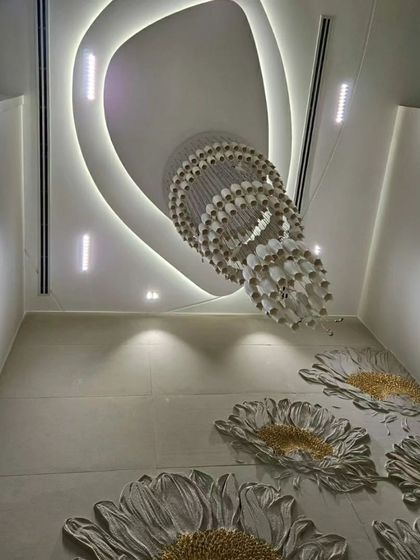 A view from below showing a stunning floral inlay on the floor, complemented by a modern, layered false ceiling and a grand crystal chandelier.