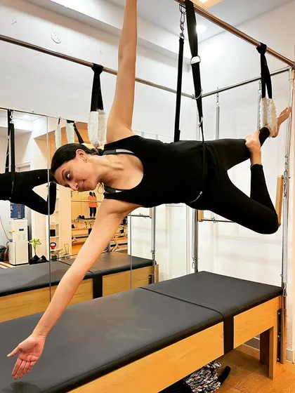 She conquers fear and smiles with confidence. This suspended pose on the Cadillac is a testament to her strength and trust in her body.