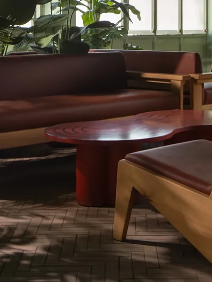 This private lounge at Sunrise showcases our approach to spatial storytelling. We designed this intimate setting with custom wooden sofas and armchairs, complemented by a bold, organically shaped coffee table, all nestled among lush greenery to create a feeling of a tranquil, stylish escape.