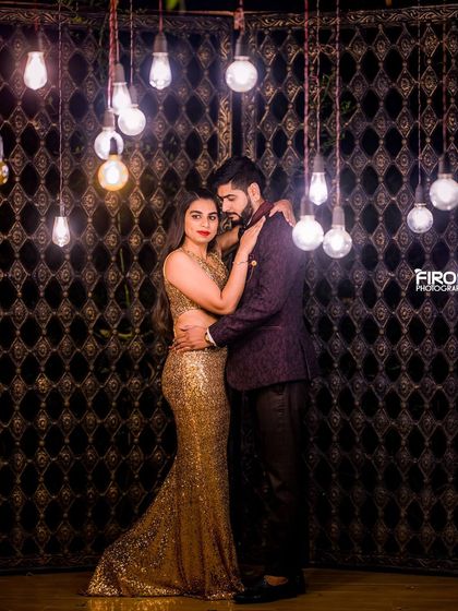 A stylish couple poses in front of the rustic gate with hanging bulbs, a perfect modern pre-wedding shot.