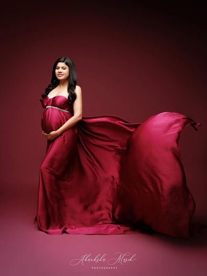 A full-length portrait in a deep magenta satin gown, with the fabric flowing to create a sense of regal drama.