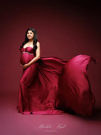 A full-length portrait in a deep magenta satin gown, with the fabric flowing to create a sense of regal drama.