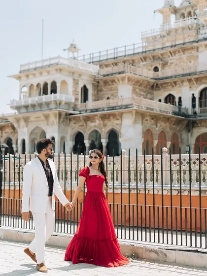 A stylish walking shot capturing the couple's modern outfits and confident stride against the classic backdrop of Albert Hall.