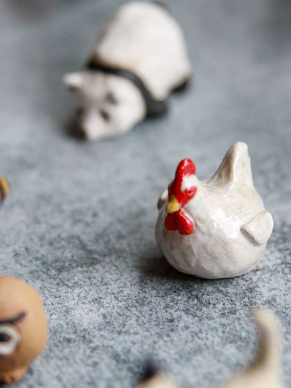 A close up of a miniature chicken with a bright red comb, sculpted with personality and charm.