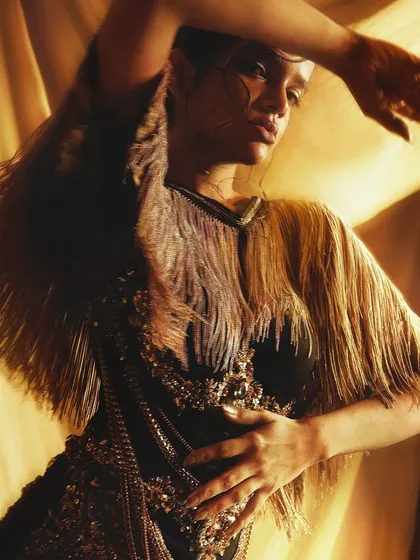 Movement and texture come together in this shot, with the gold makeup tying into the metallic fringe of the outfit.
