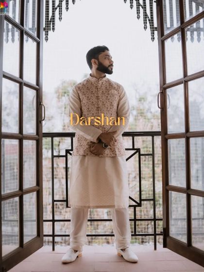A full-length portrait of the groom, Darshan, framed by a beautiful doorway. His elegant ethnic wear and confident pose make for a striking image.
